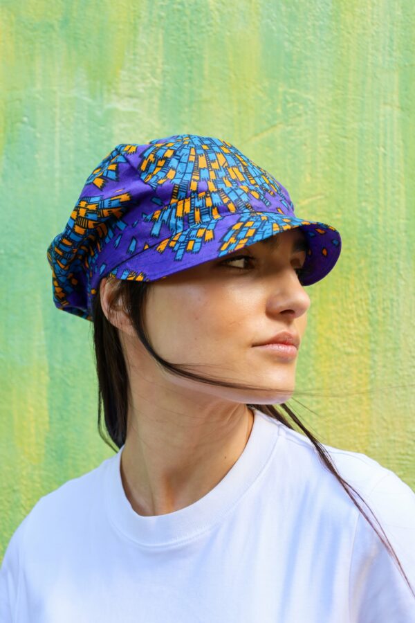 Gorra con estampado africano en tonos morado, azul y amarillo. Tejida a mano. Moda ética, única y con estilo.
