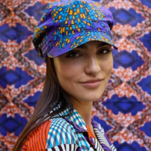 Gorra con estampado africano en tonos morado, azul y amarillo. Tejida a mano. Moda ética, única y con estilo.